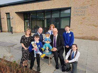 Deputy First Minister John Swinney with Headteacher Sally McLean and Ethan, Niamh, Archie and Kayleigh (and Monty the mascot and Muir Wullie) at the official opening of Muirfield Primary School