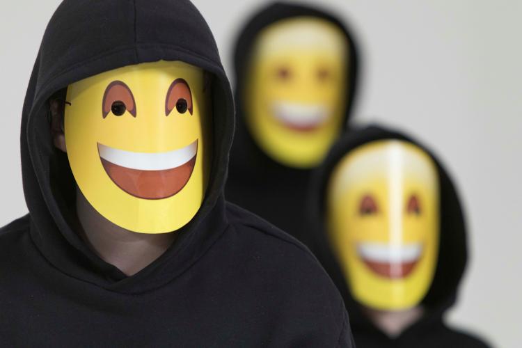 three young people with emoji style face masks on