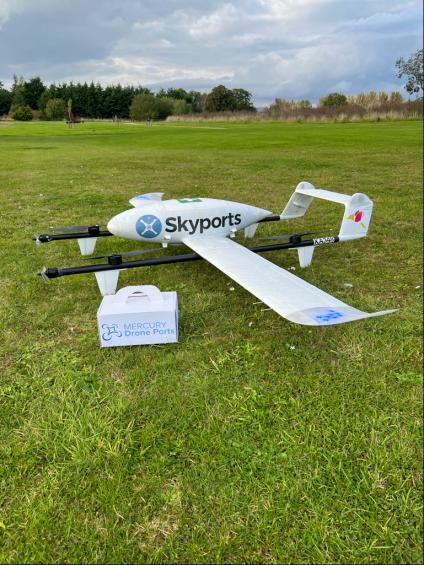 White drone with a Mercury Drone Ports box sat beside it.