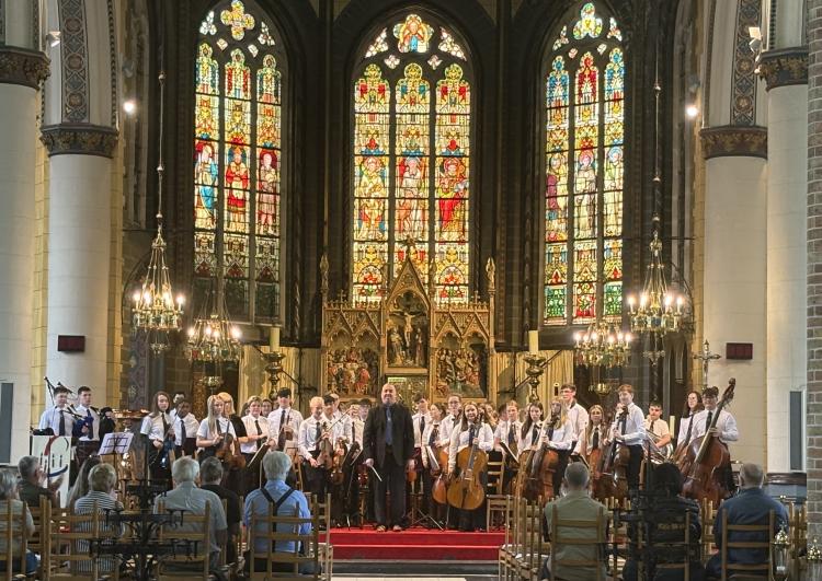 Photo of full orchestra on stage on their Belgium tour